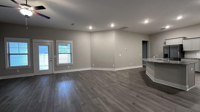 kitchen with dark wood-style flooring, visible vents, a sink, black fridge, and open floor plan