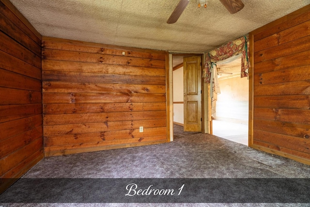 spare room featuring a textured ceiling, carpet, and wooden walls