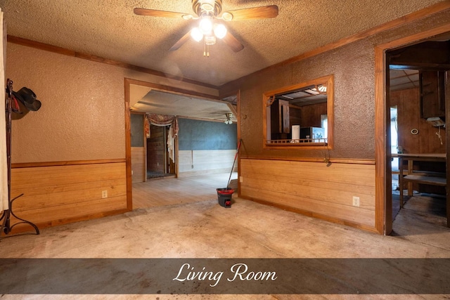 carpeted spare room with wainscoting, a textured ceiling, a textured wall, and a ceiling fan
