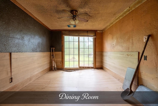 spare room featuring ceiling fan, a textured wall, and wood finished floors