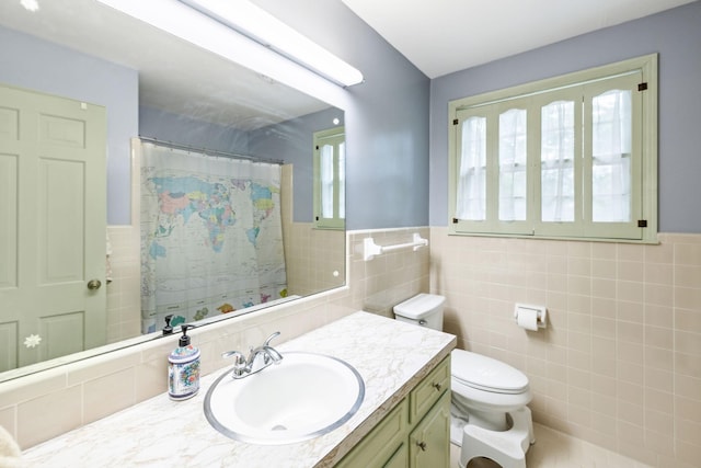 full bathroom with toilet, a shower with curtain, a wainscoted wall, tile walls, and vanity