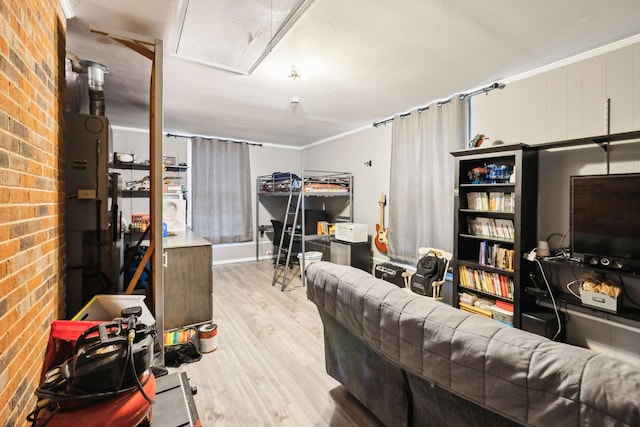 living area with attic access, wood finished floors, and brick wall