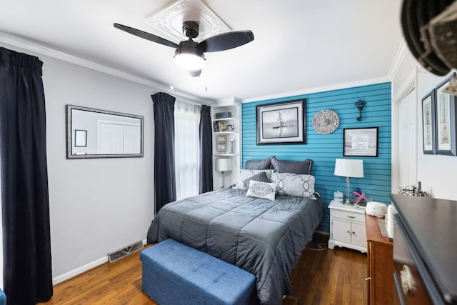 bedroom featuring baseboards, ornamental molding, visible vents, and wood finished floors