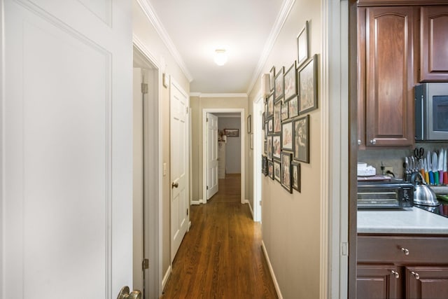 corridor featuring crown molding, a toaster, dark wood-type flooring, and baseboards