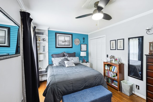 bedroom featuring wood finished floors, a closet, crown molding, baseboards, and ceiling fan
