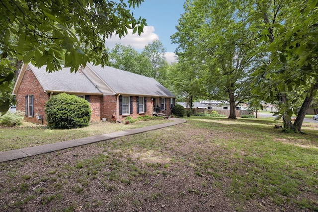 single story home with roof with shingles, fence, brick siding, and a front yard