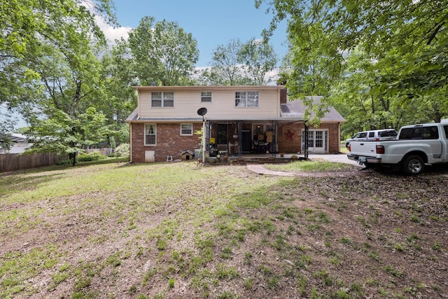rear view of property with fence, a patio, brick siding, and a lawn