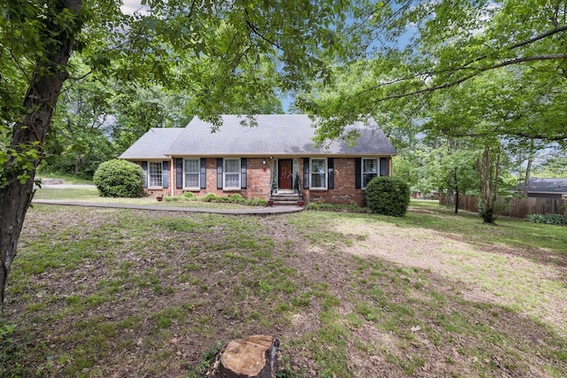 ranch-style home with a front lawn, brick siding, roof with shingles, and fence