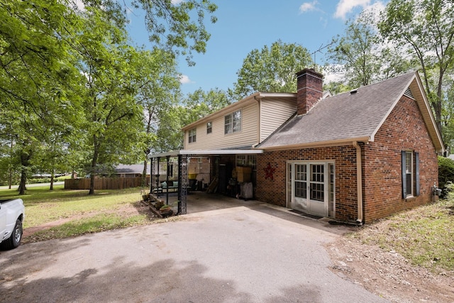 back of house with a chimney, fence, aphalt driveway, a shingled roof, and brick siding