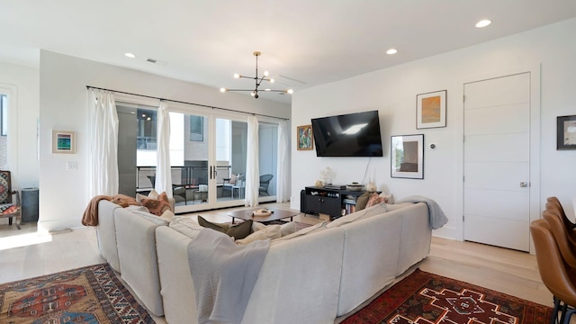 living area with an inviting chandelier, recessed lighting, visible vents, and wood finished floors