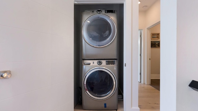 laundry area featuring laundry area, stacked washing maching and dryer, and wood finished floors