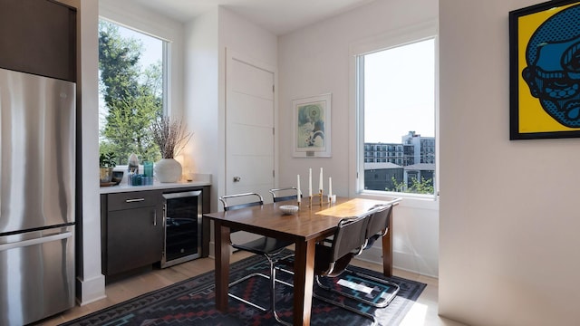 dining area with light wood-style floors and beverage cooler