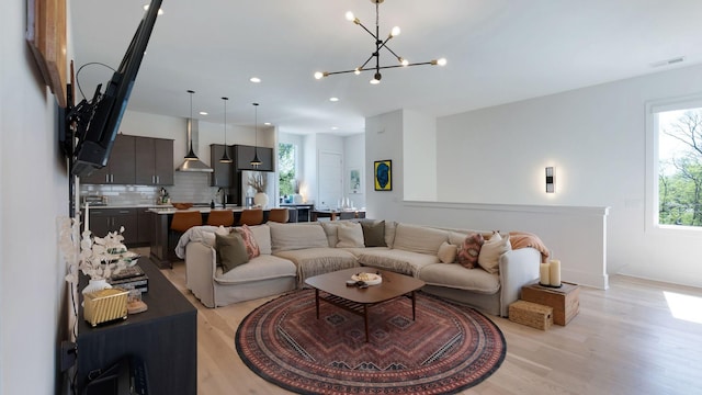 living room featuring an inviting chandelier, light wood-style floors, visible vents, and recessed lighting
