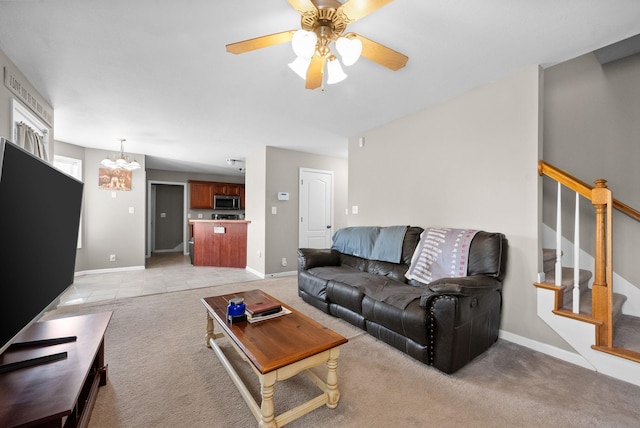 3144 Holly Pt, Clarksville, TN 37043 - living room featuring light colored carpet, stairway, baseboards, and ceiling fan with notable chandelier