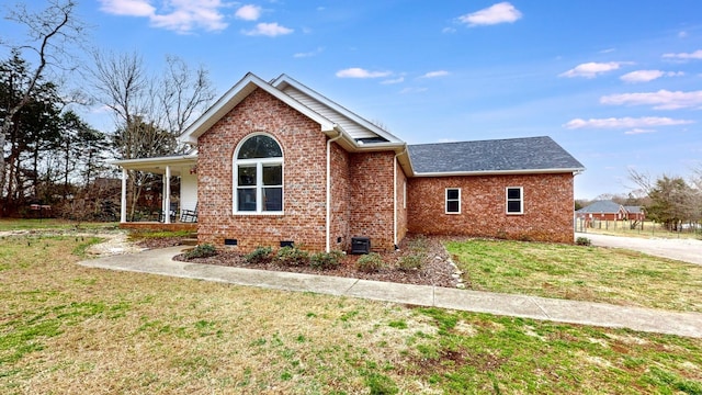 view of front of home featuring a front yard, brick siding, covered porch, and crawl space