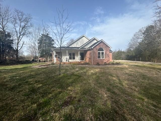 view of front facade featuring a porch, brick siding, and a front yard