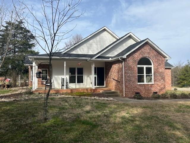 view of front of house featuring covered porch, brick siding, crawl space, and a front yard