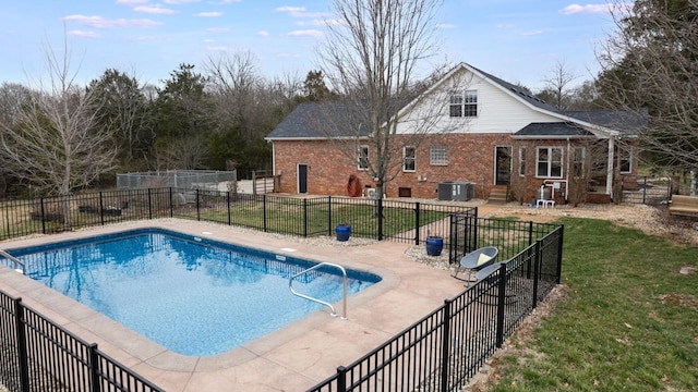 view of swimming pool with fence, a lawn, central AC unit, a patio area, and a fenced in pool