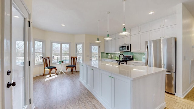 kitchen featuring stainless steel appliances, baseboards, white cabinets, and light wood-style floors