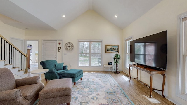 living room with high vaulted ceiling, stairs, light wood-style flooring, and recessed lighting