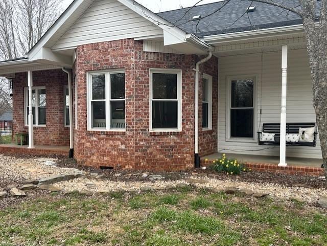 back of house with covered porch and brick siding