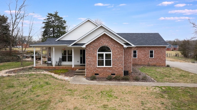 view of front facade featuring brick siding, covered porch, crawl space, a front yard, and roof with shingles