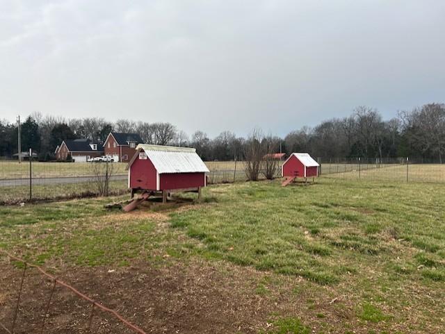 view of yard featuring exterior structure, a rural view, an outbuilding, and fence