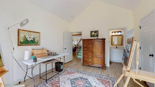 home office with light wood finished floors, high vaulted ceiling, and a sink