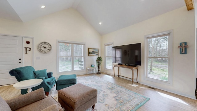 living area featuring baseboards, high vaulted ceiling, a healthy amount of sunlight, and wood finished floors