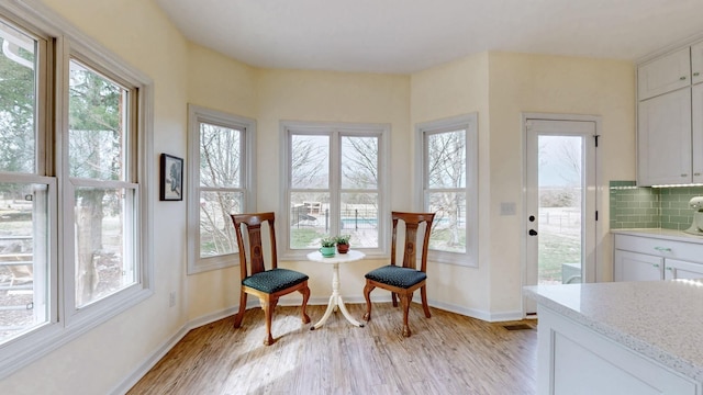 sitting room featuring light wood-type flooring, baseboards, and a healthy amount of sunlight