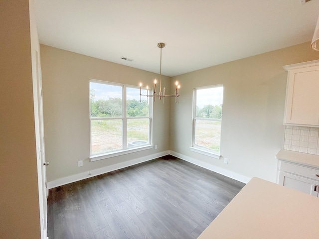 unfurnished dining area with an inviting chandelier, visible vents, a healthy amount of sunlight, and dark wood-type flooring