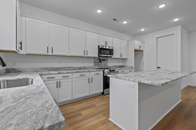 3313 Parker Ln, Chattanooga, TN 37419 - kitchen with stainless steel appliances, a sink, white cabinets, light wood finished floors, and recessed lighting