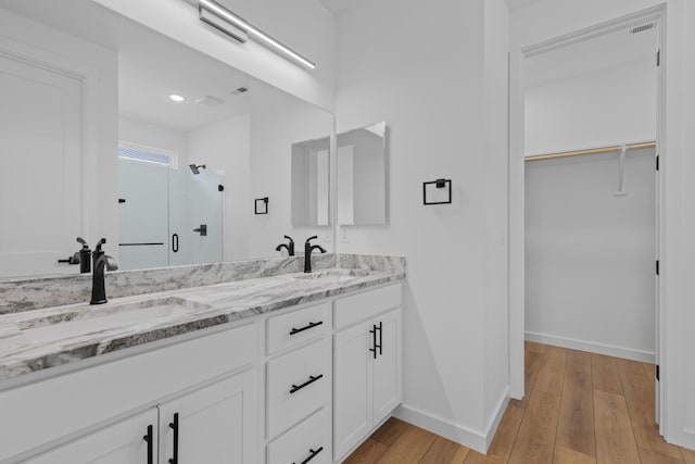 3313 Parker Ln, Chattanooga, TN 37419 - full bathroom featuring double vanity, baseboards, a shower stall, wood finished floors, and a spacious closet