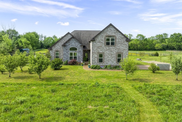 rear view of property with fence, brick siding, and a lawn