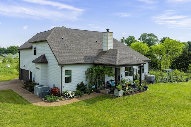 back of property featuring a chimney, a yard, an attached garage, central air condition unit, and a shingled roof