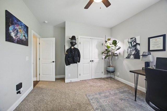carpeted office space featuring baseboards and ceiling fan