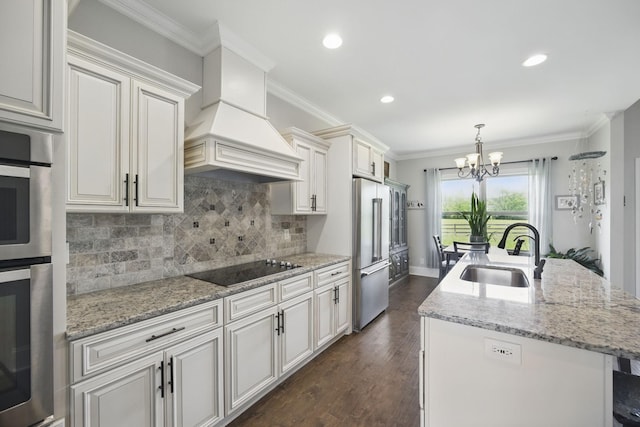 kitchen featuring high end fridge, a sink, dark wood-type flooring, black electric cooktop, and a chandelier