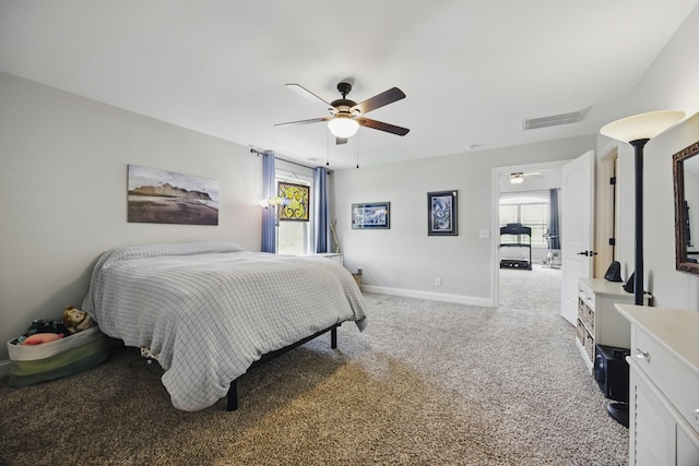 bedroom featuring light colored carpet, multiple windows, visible vents, and a ceiling fan