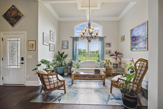 sitting room with an inviting chandelier, a towering ceiling, crown molding, and wood finished floors