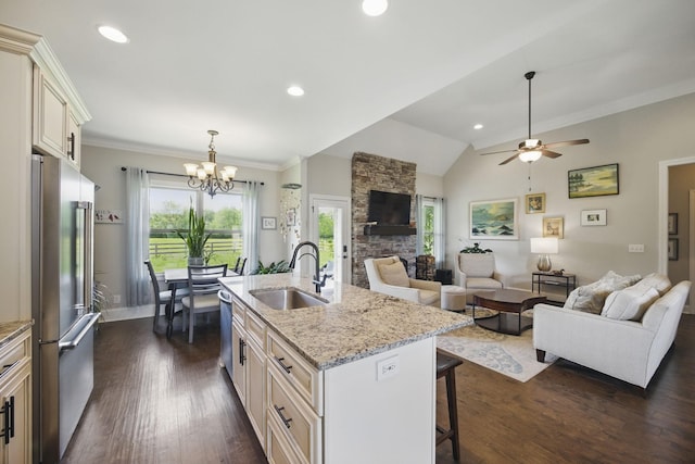 kitchen with stainless steel appliances, open floor plan, a sink, and a breakfast bar area