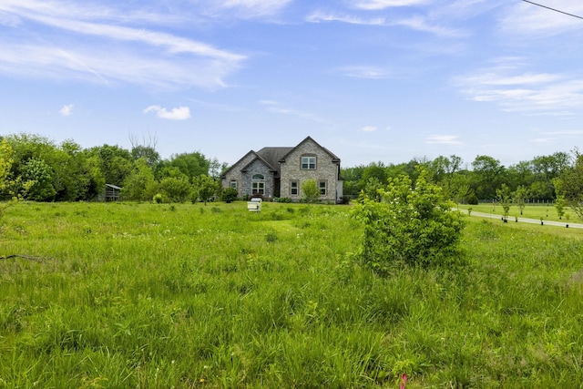 view of front of property featuring a rural view, stone siding, and a barn