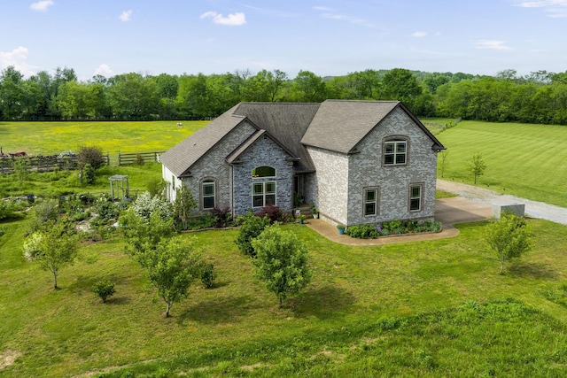view of front of home with a rural view, stone siding, and a front yard