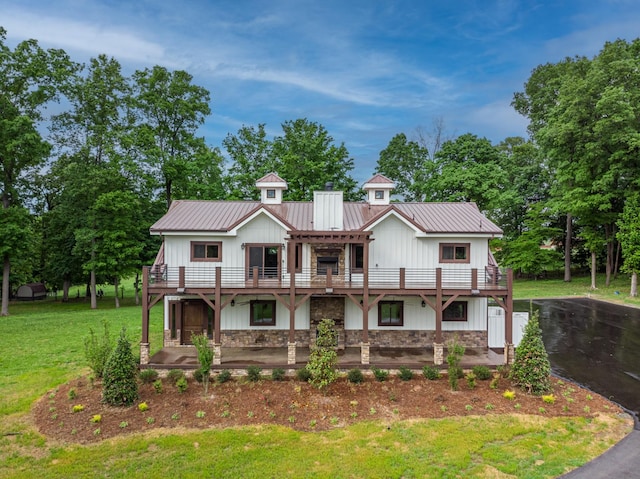 view of front of home with stone siding, board and batten siding, metal roof, and a front yard