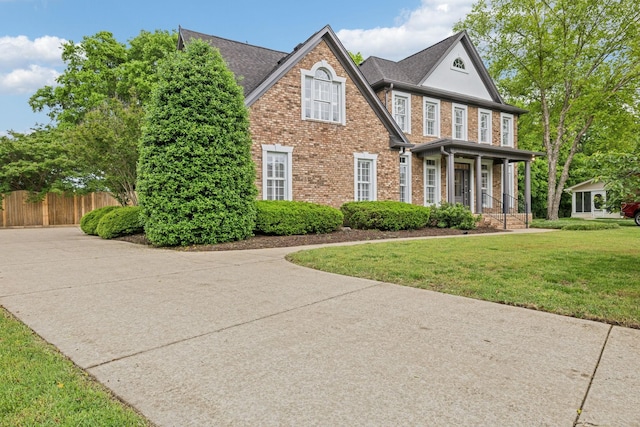 1207 Mullberry Ct, Murfreesboro, TN 37130 - traditional-style house with brick siding, fence, a porch, roof with shingles, and a front lawn