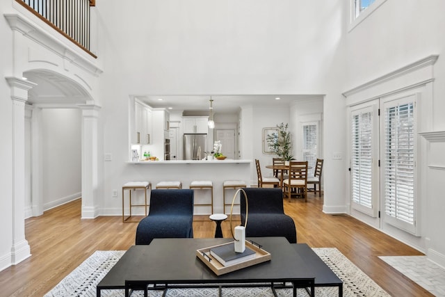 1207 Mullberry Ct, Murfreesboro, TN 37130 - living room featuring light wood-type flooring, a high ceiling, baseboards, and ornate columns