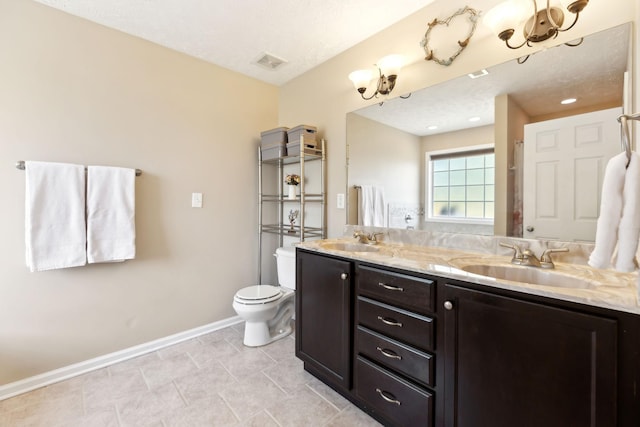 bathroom featuring baseboards, toilet, and double vanity