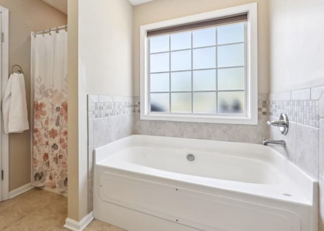 full bath with healthy amount of natural light, a garden tub, baseboards, and tile patterned flooring