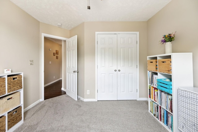 carpeted bedroom featuring a closet, baseboards, and a textured ceiling