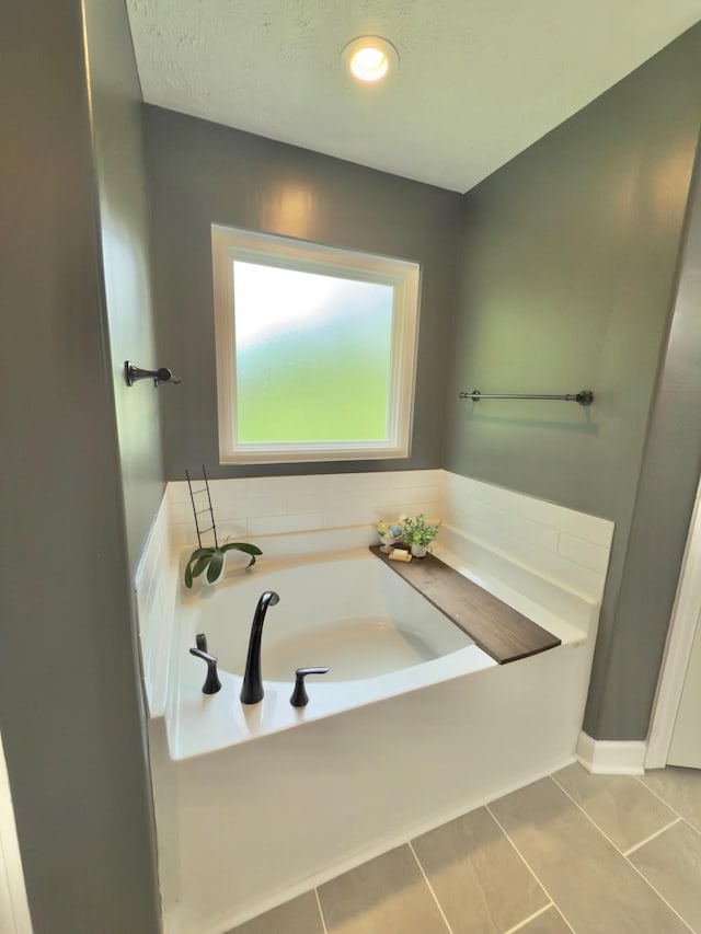 full bath featuring baseboards, tile patterned floors, and a garden tub