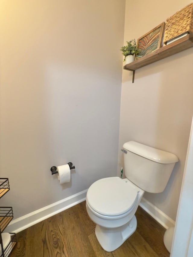 bathroom with toilet, baseboards, and wood finished floors